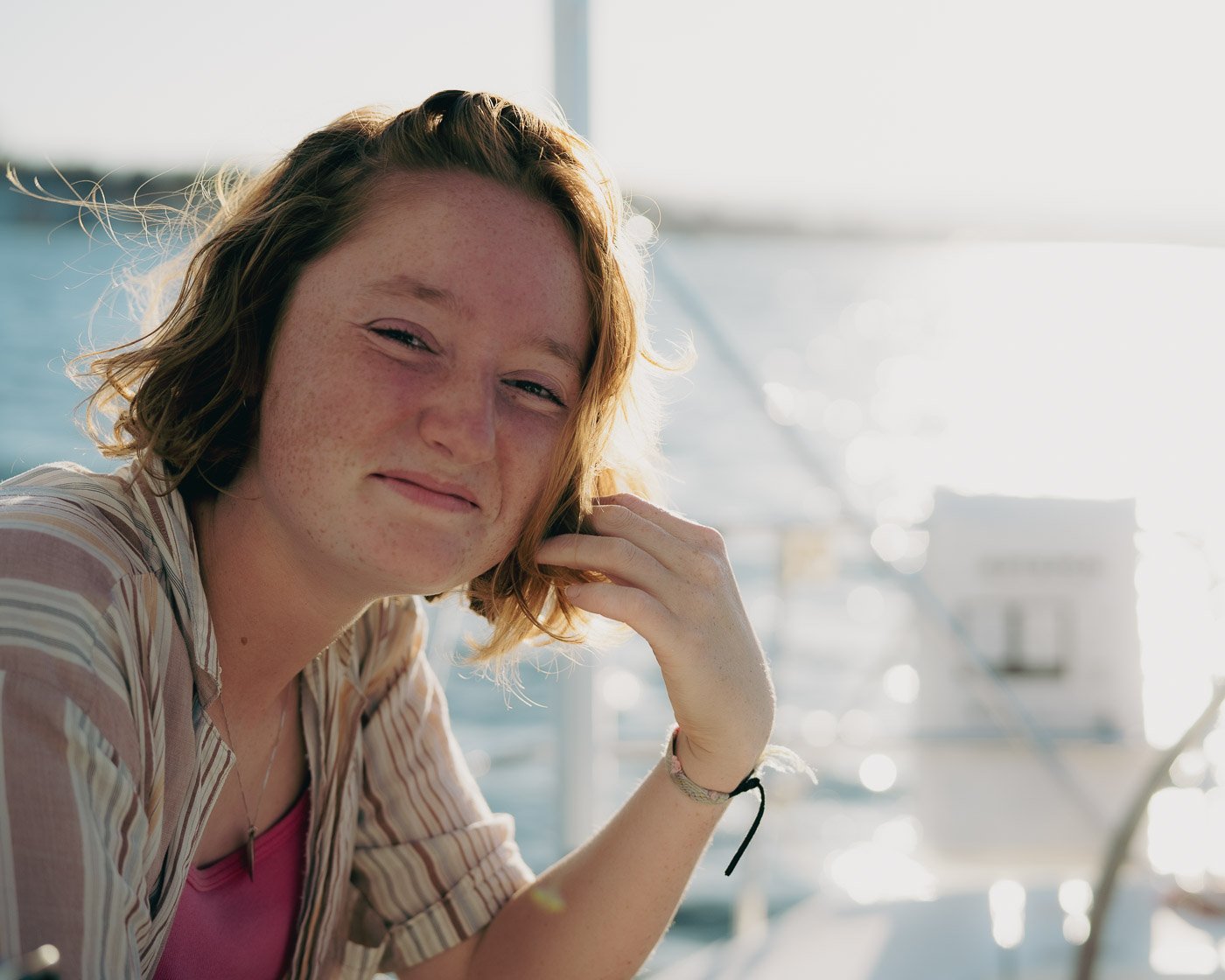 Smiling girl playing with her hair on a sail boat