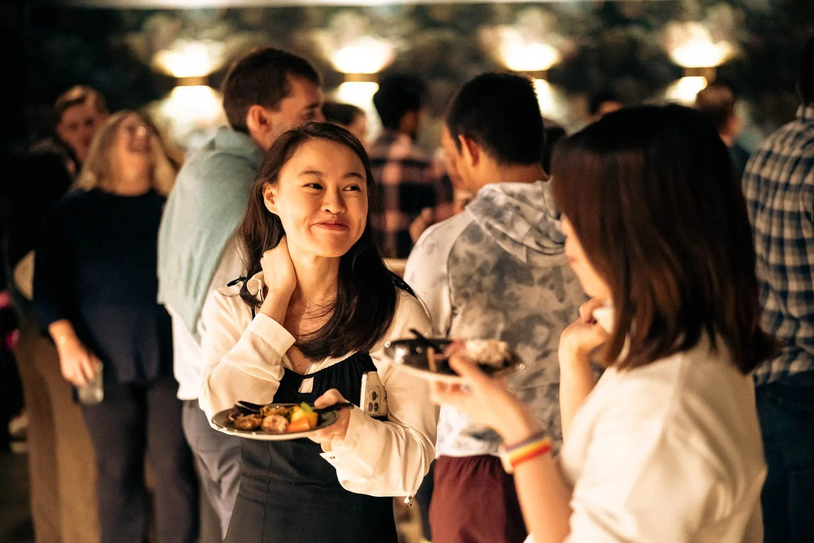 Smiling woman eating bar food in a crowded room at Sousol