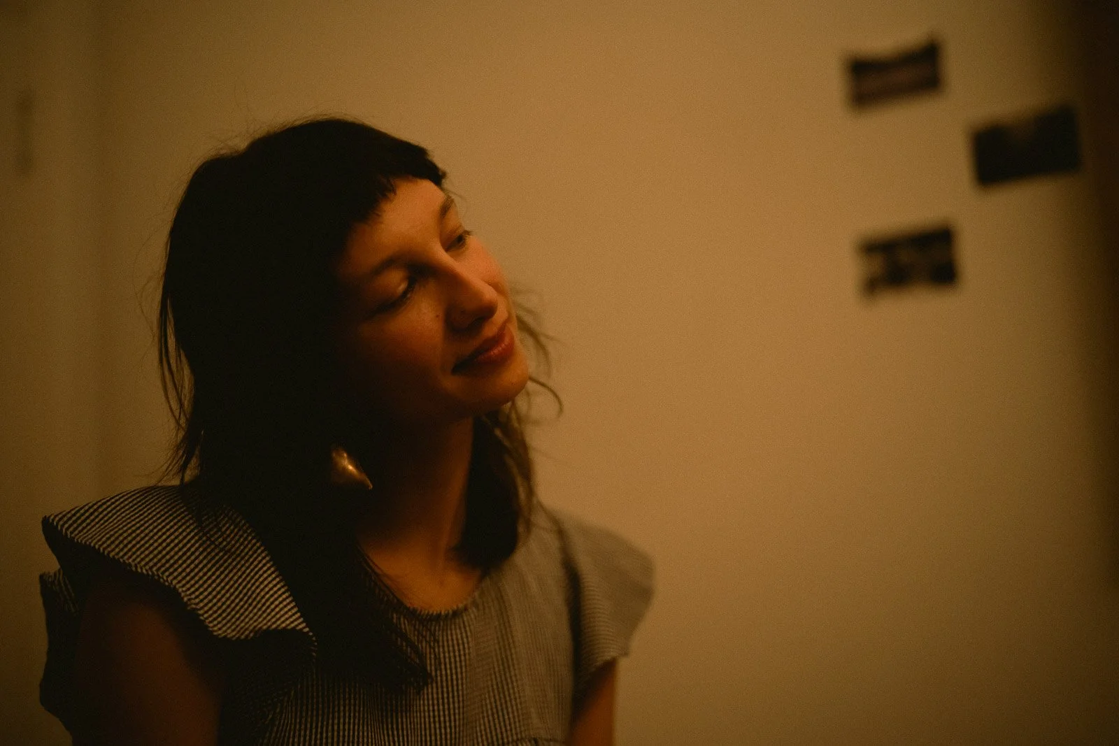 An elegant woman smiling with her eyes closed in a warmly lit room