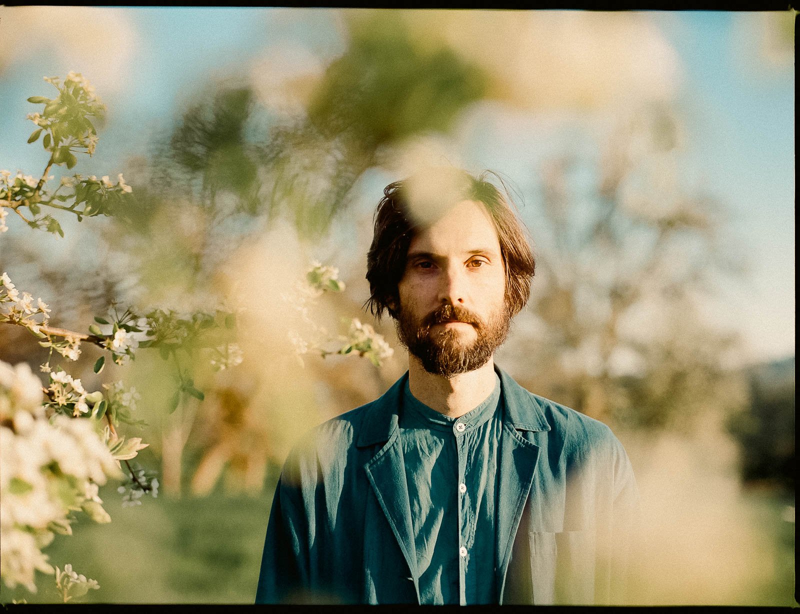 Portrait of Portland musician, Greg Allison, in a field surrounded by white flowers