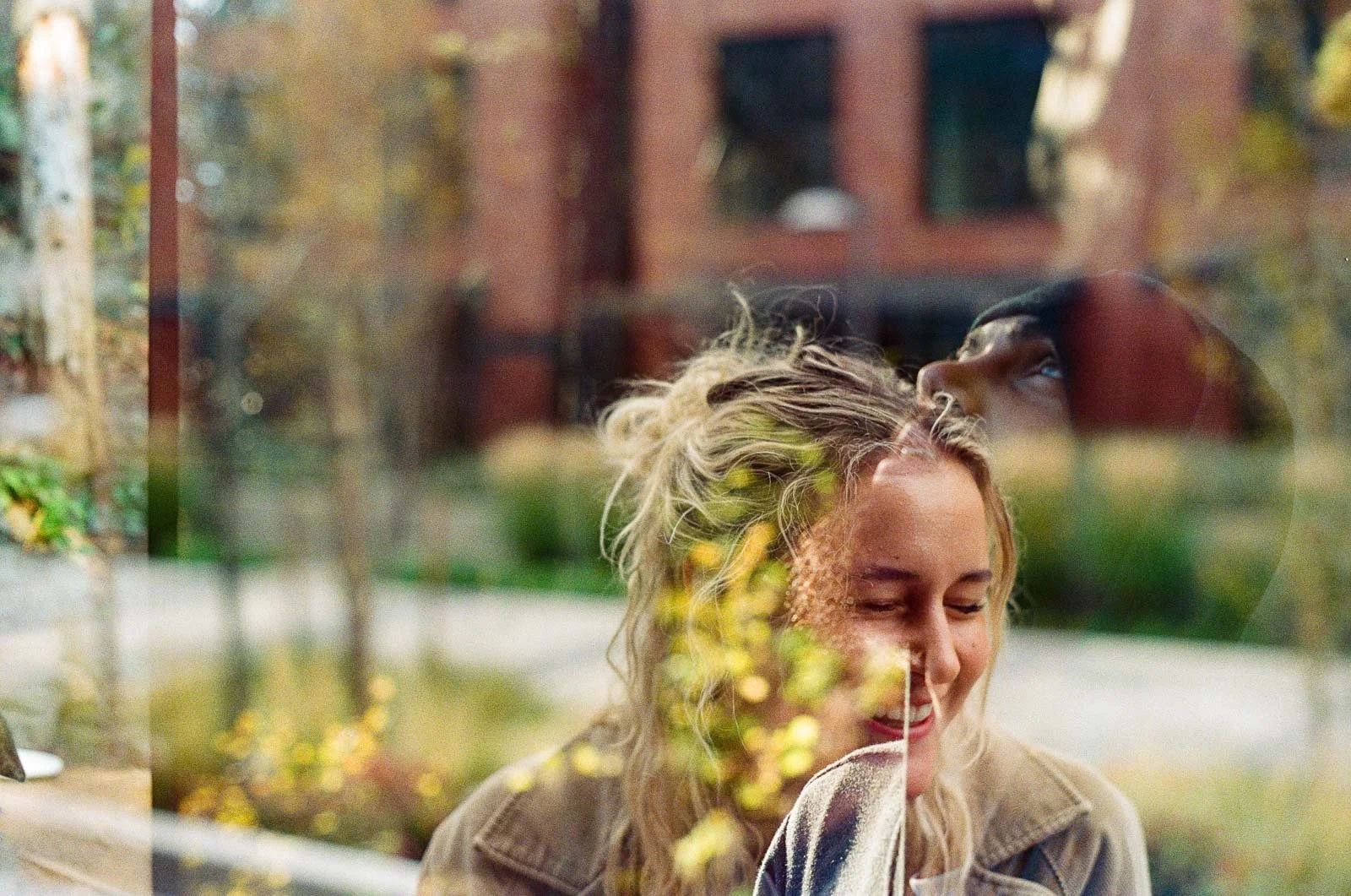 Double exposure of a girl laughing in front of a red brick building