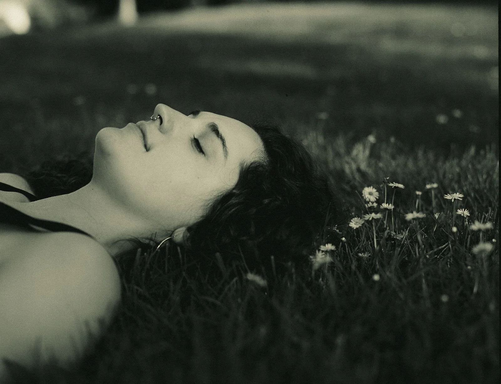 A girl laying in a field surrounded by daisies