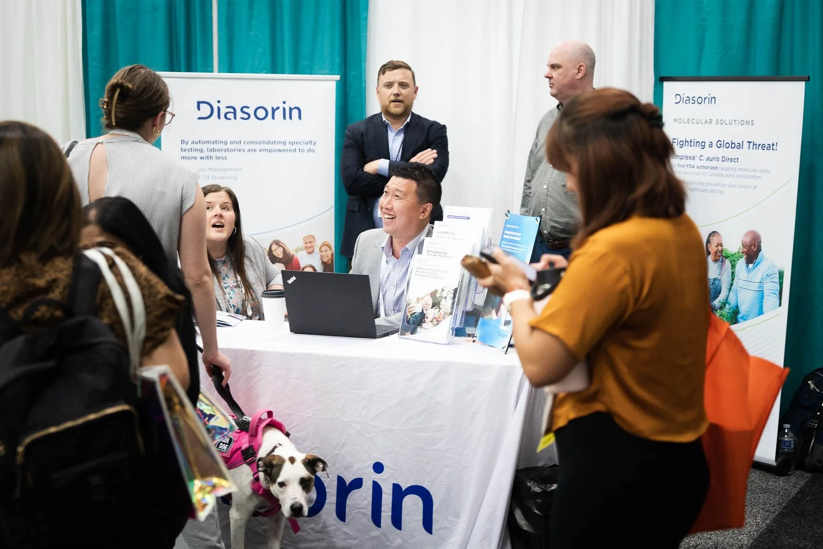 Smiling people presenting information at an expo booth for a medical conference