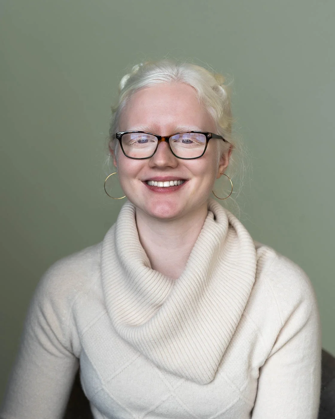 Headshot of a young woman dressed all in white, with a light green background