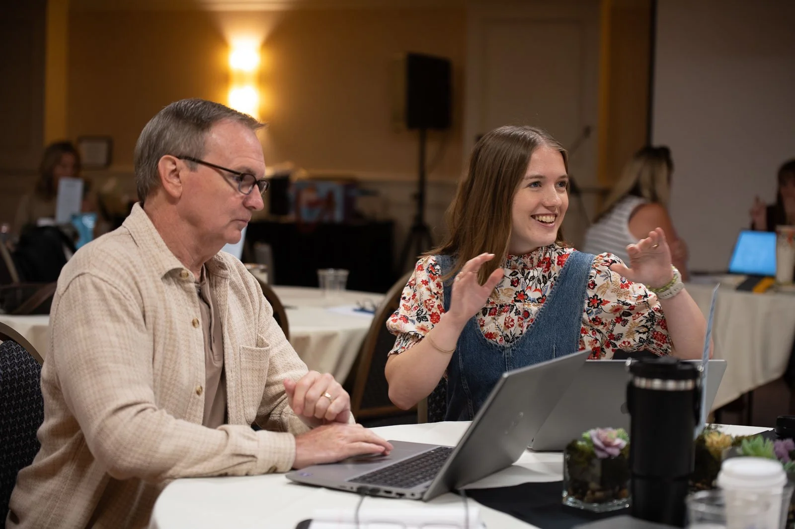Two people at a table with a laptop at the Roundtree Agency Conference