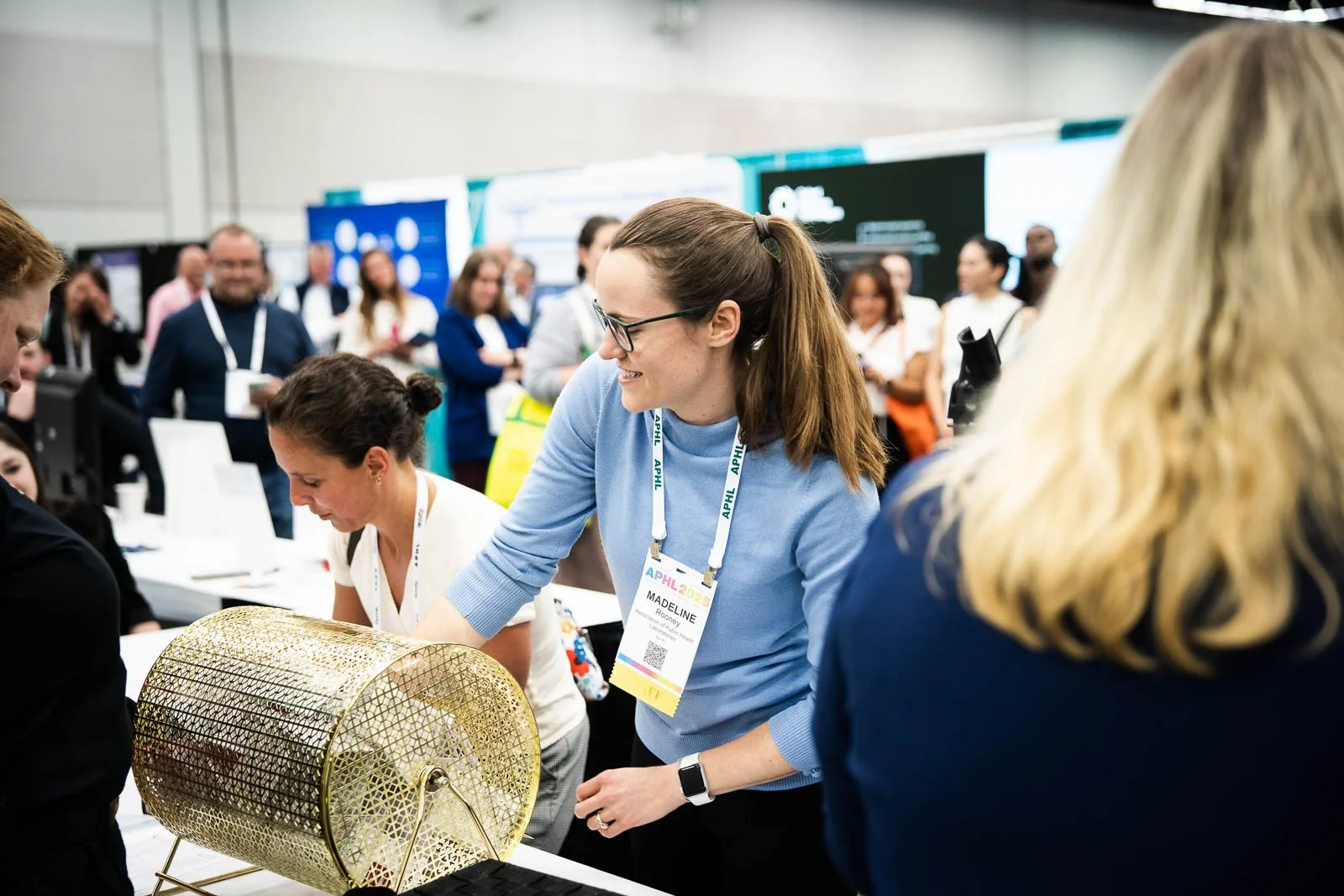 A smiling woman raffles tickets surrounded by expo booths