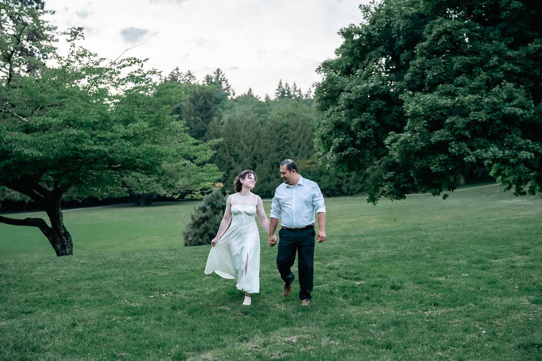 A couple walking hand in hand across a green meadow