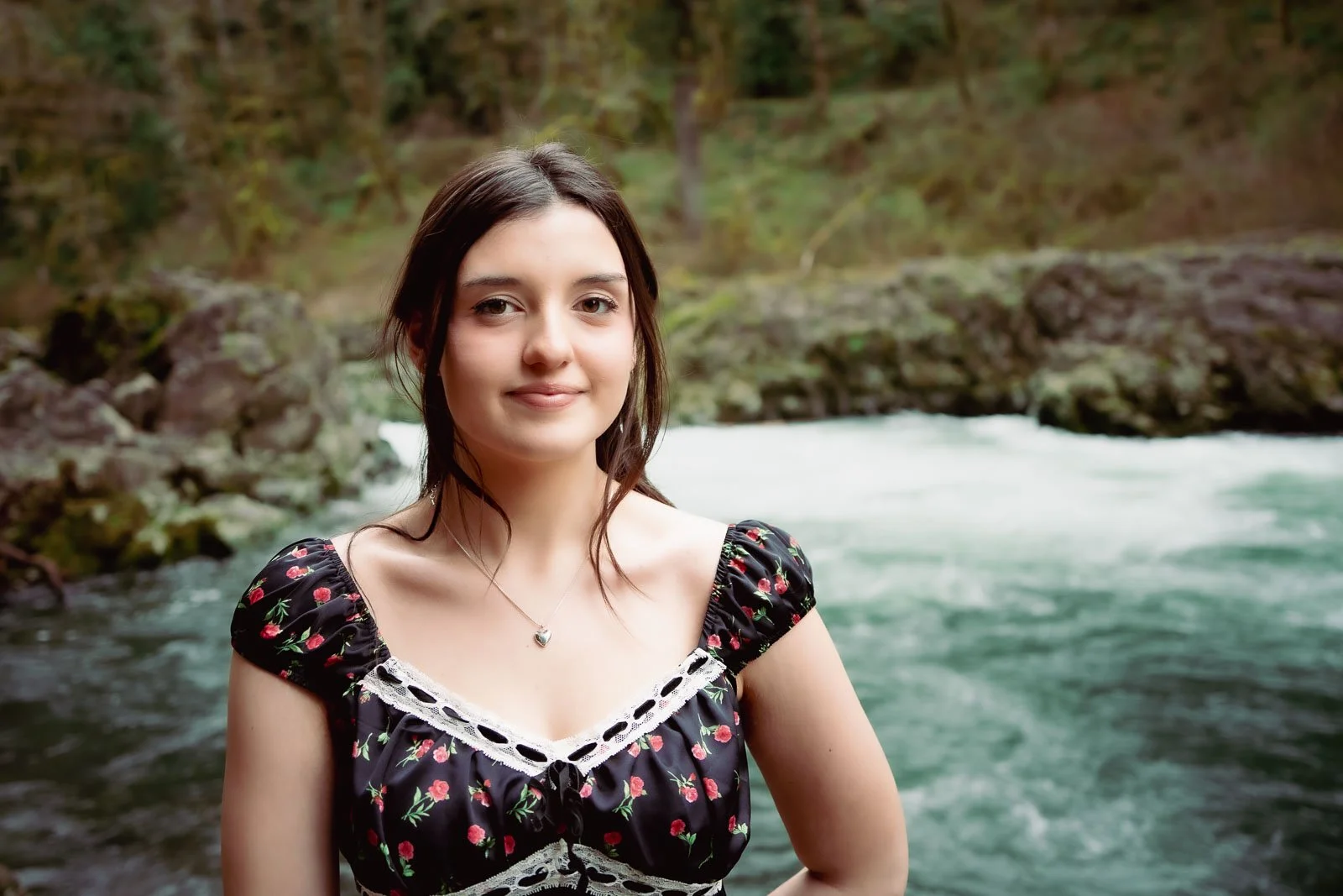 Smiling girl in a black dress next to a river