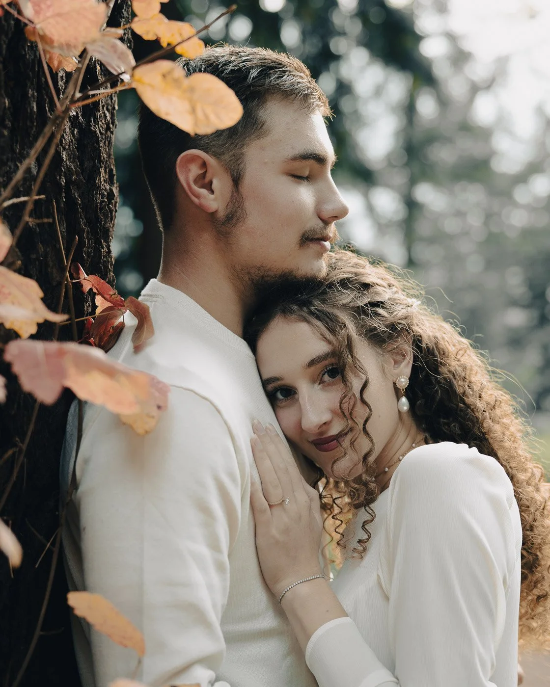 Couple in matching white, surrounded by fall colored leaves