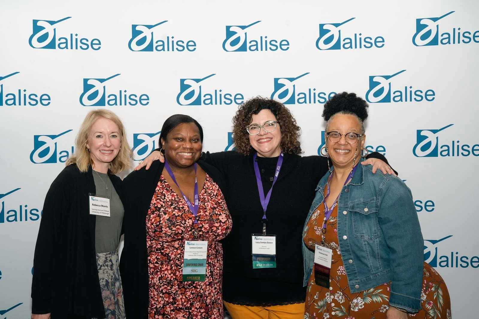 Four smiling women in front of a step and repeat, for the ALISE award ceremony