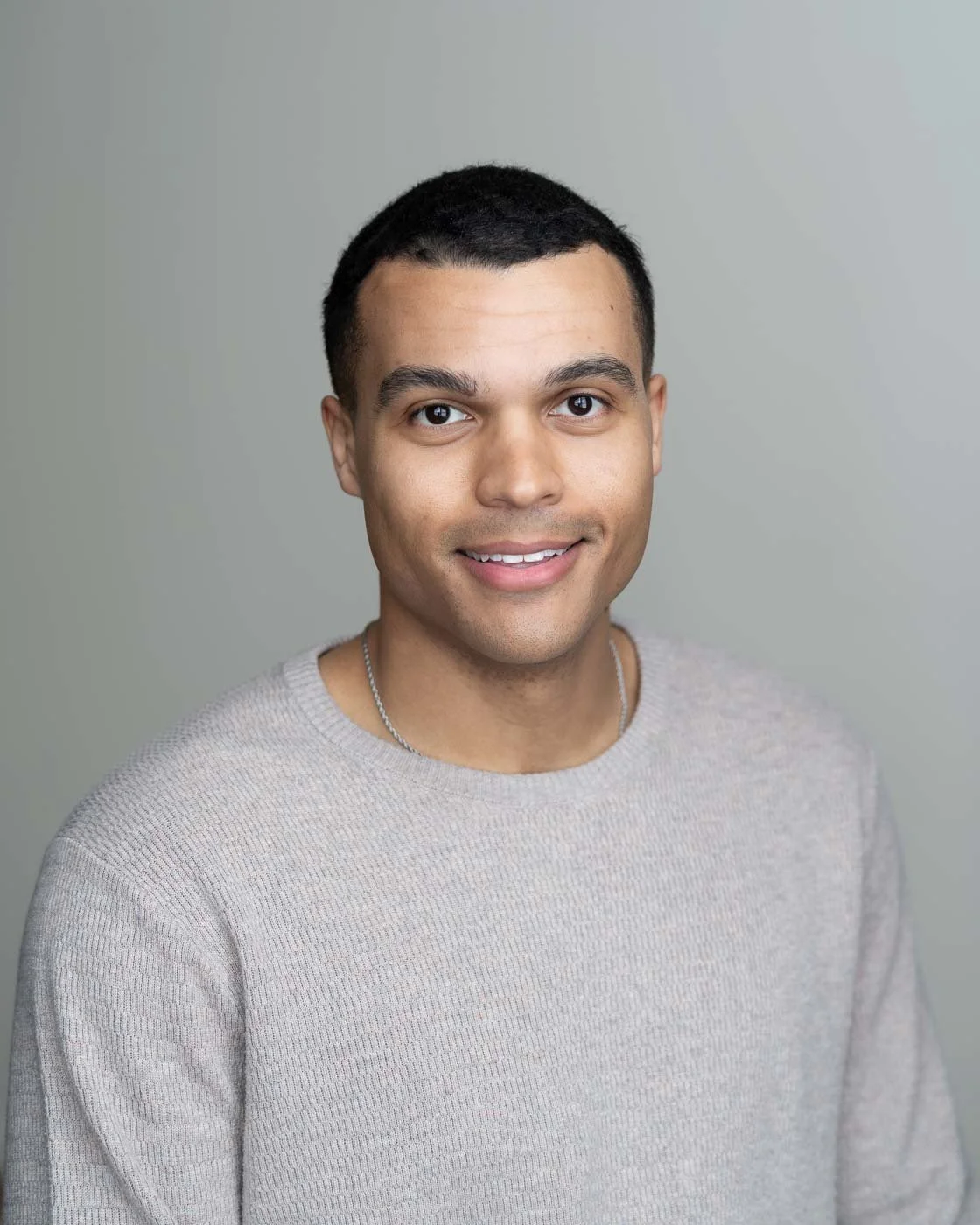 Stylish headshot of a man in a tan pullover