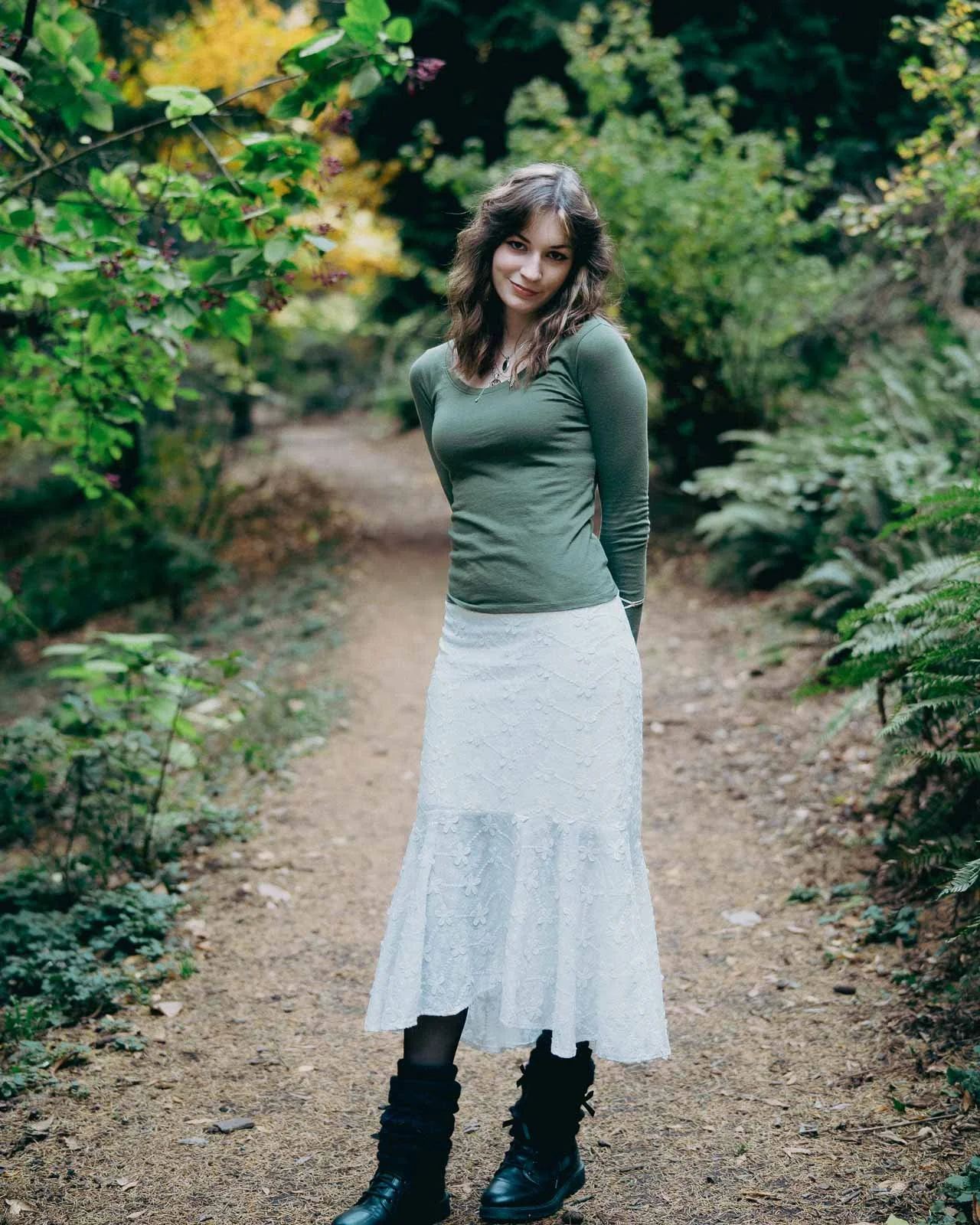 A tall girl poses for her senior portrait on a path in a Portland park