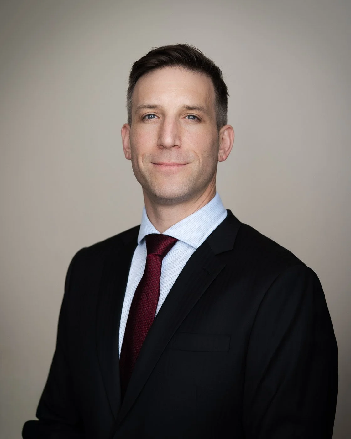 Headshot of a young man in a suit with a red tie