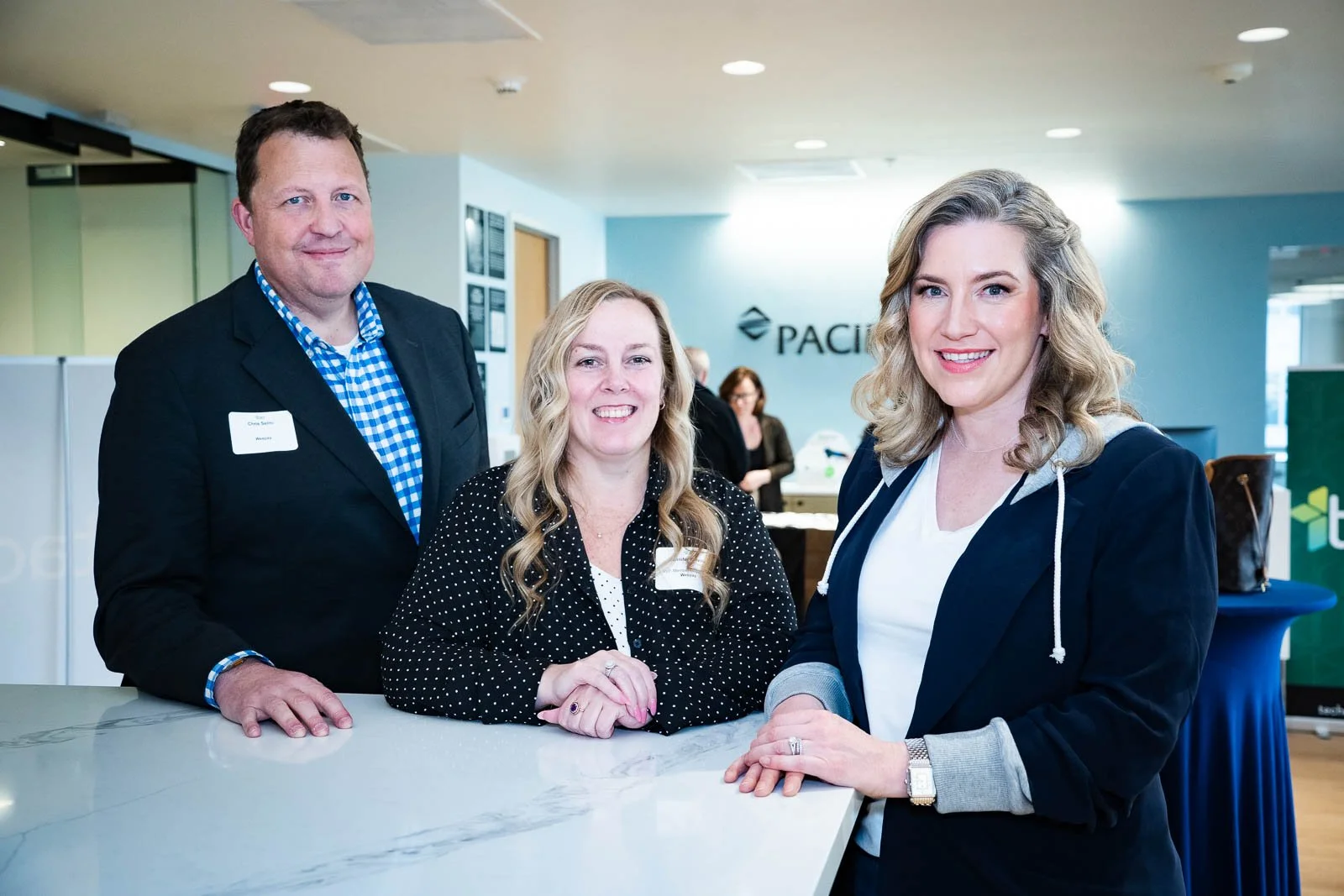 Three people smiling in front of the Pacific West Bank sign