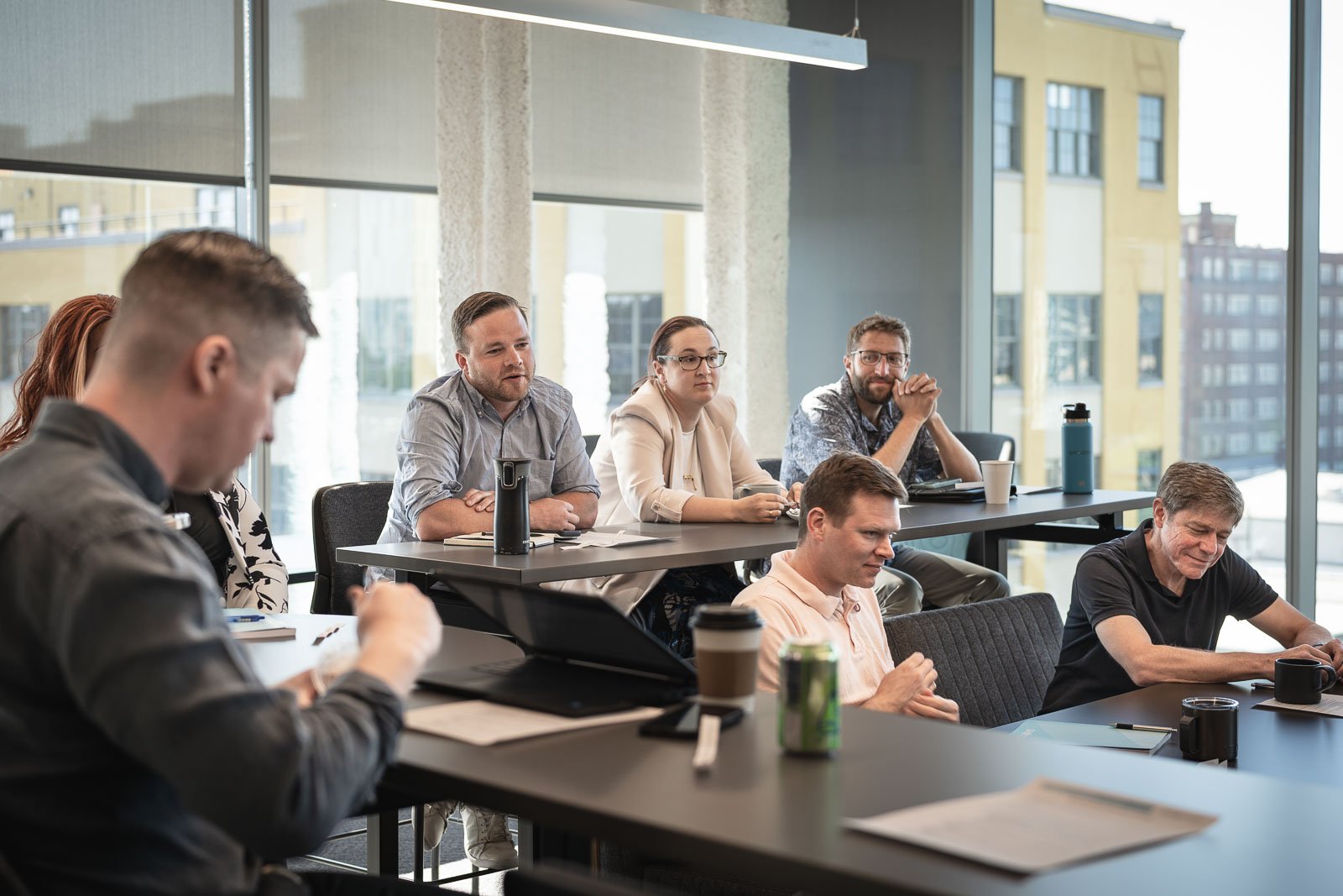 A group of employees attending a work meeting in a building with large windows