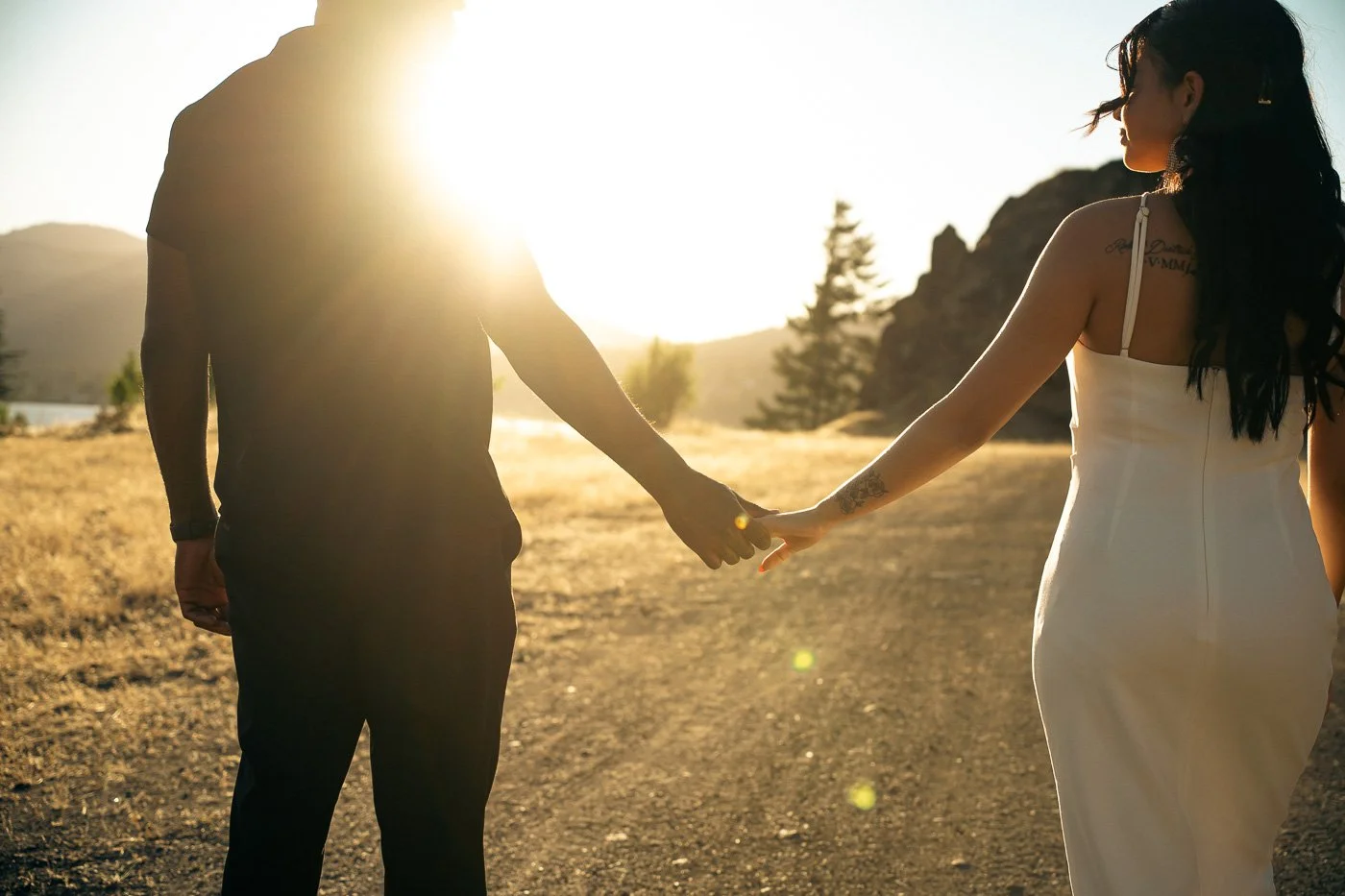 A couple walking down a road at golden hour holding hands