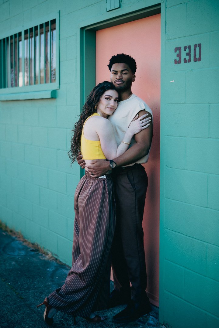 Stylish couples in front of a pastel colored building