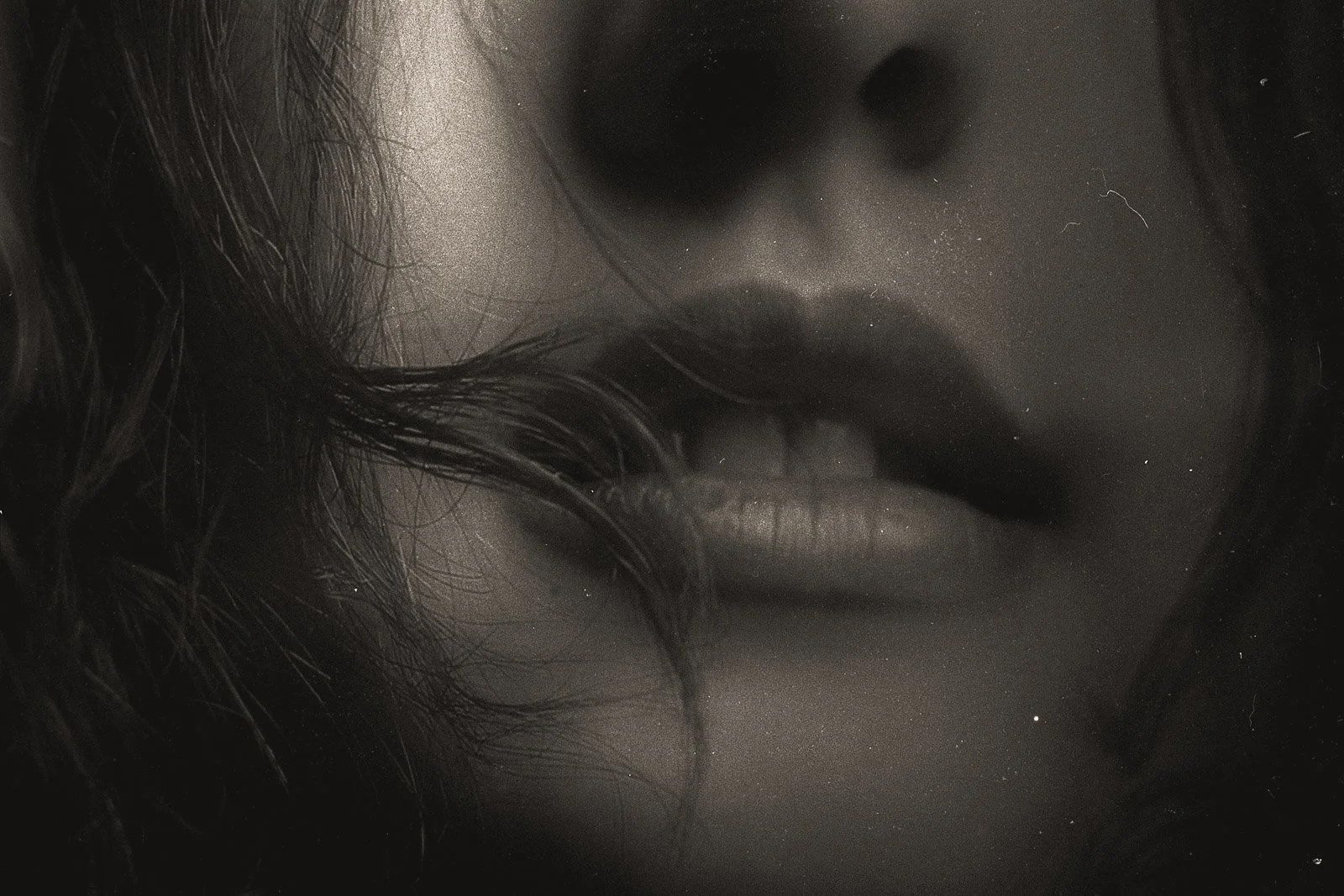 The partially open mouth of a girl with her hair framing her face