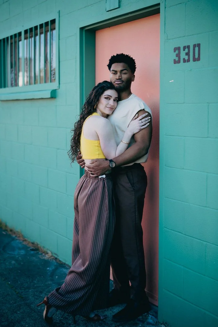 A stylish couple in front of building with pastel colors