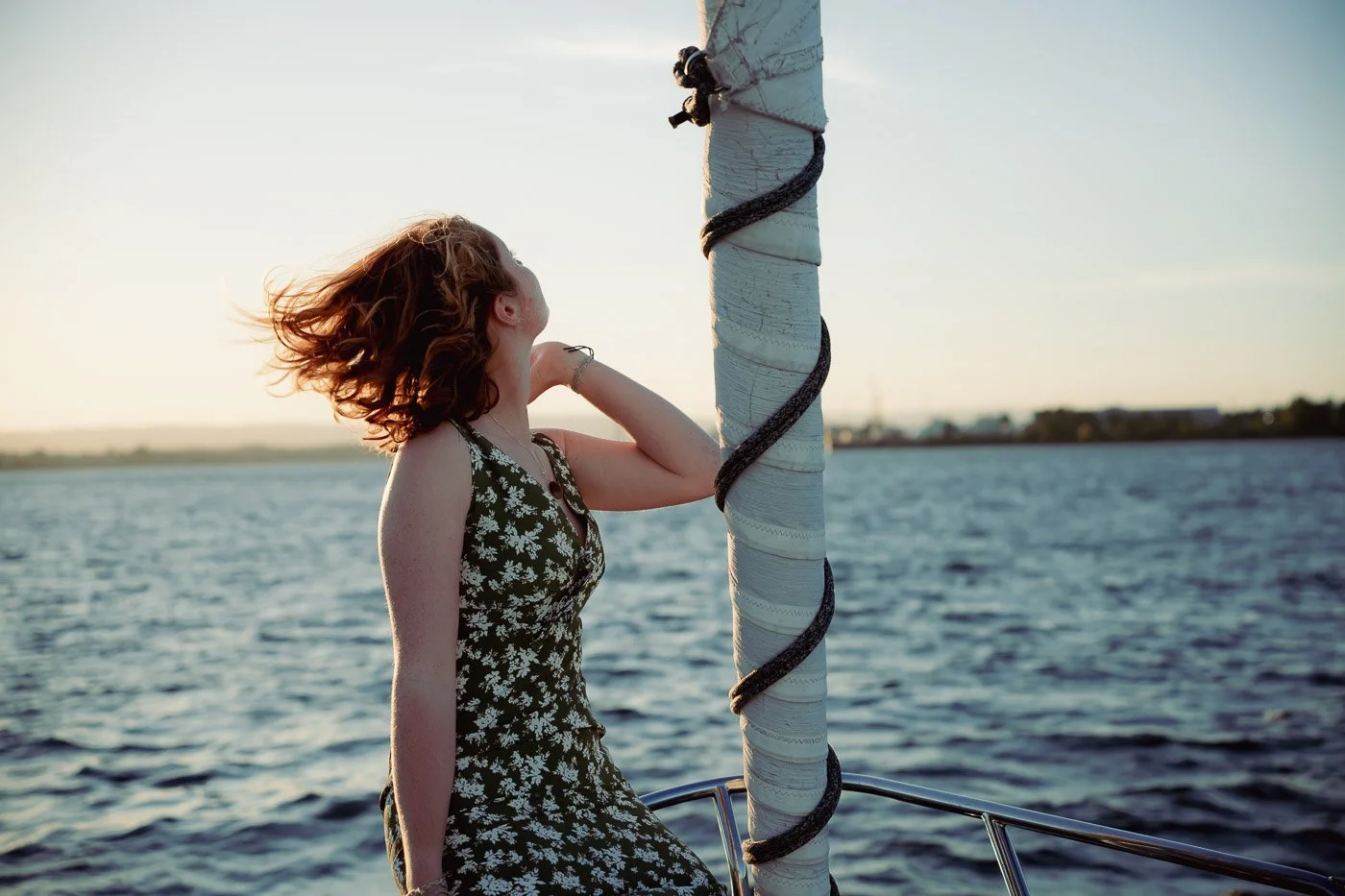 A girls hair blowing in the wind on her sailboat