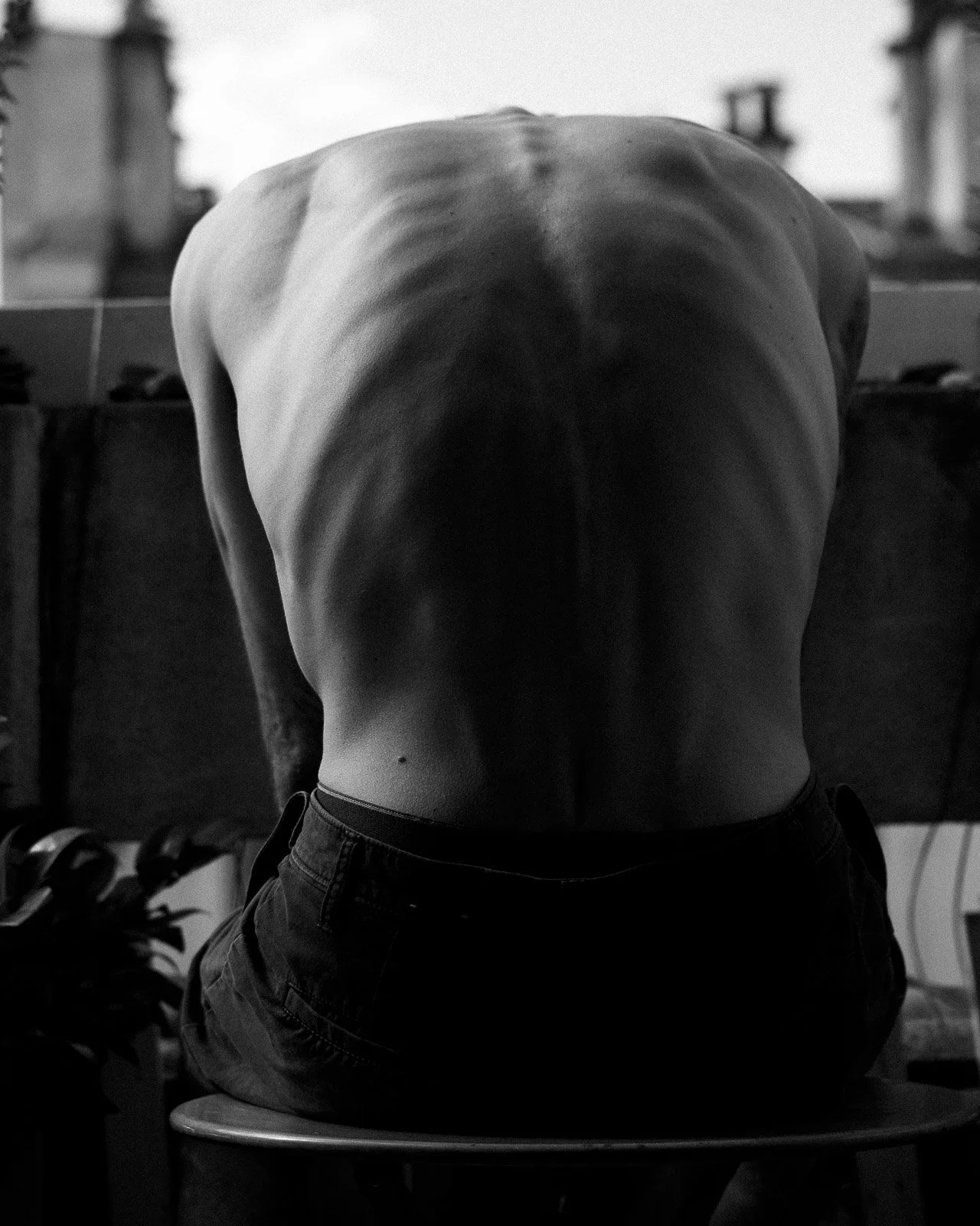 A man sitting hunched over, the ribs on his back showing