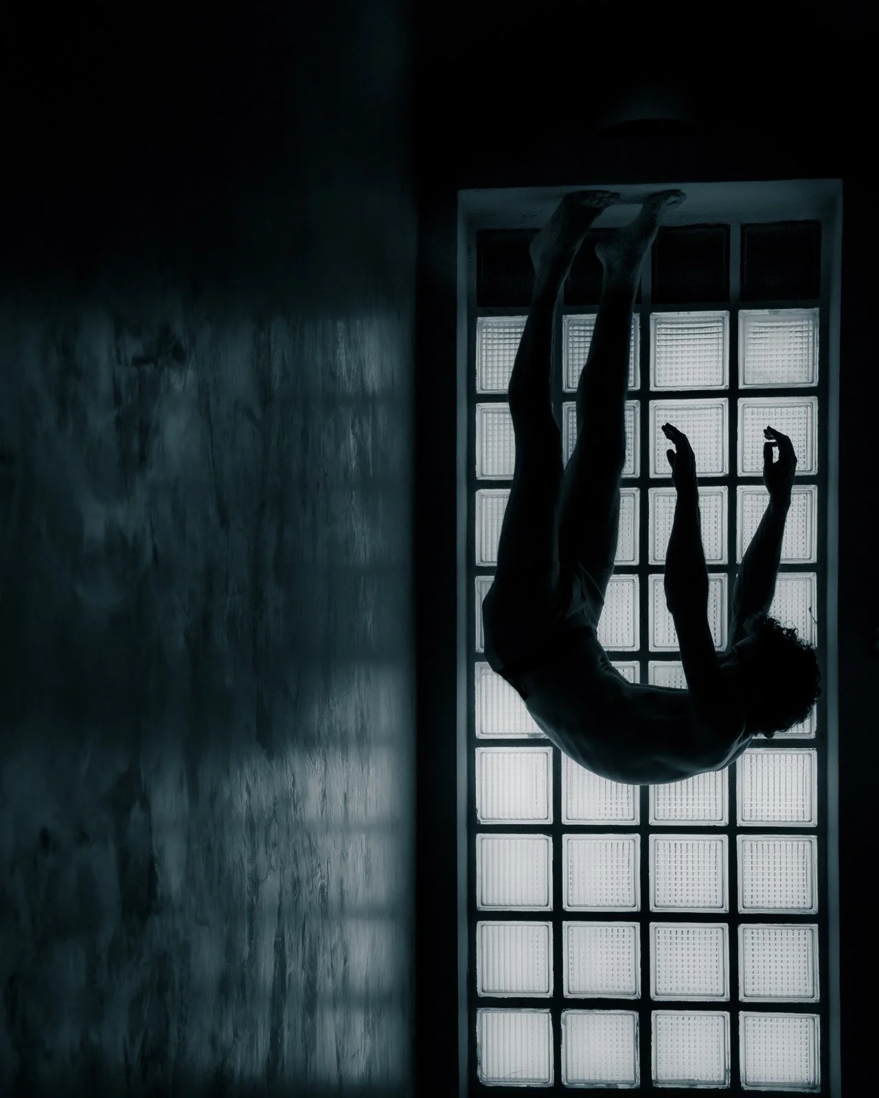 A man falling upside down in front of a large checkered windown