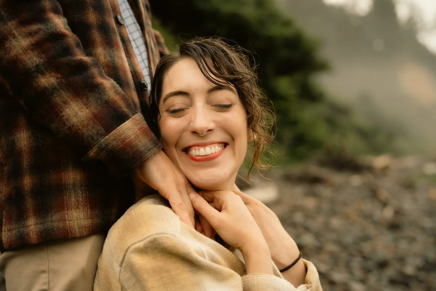 A smiling woman being held by her fiance on the beach