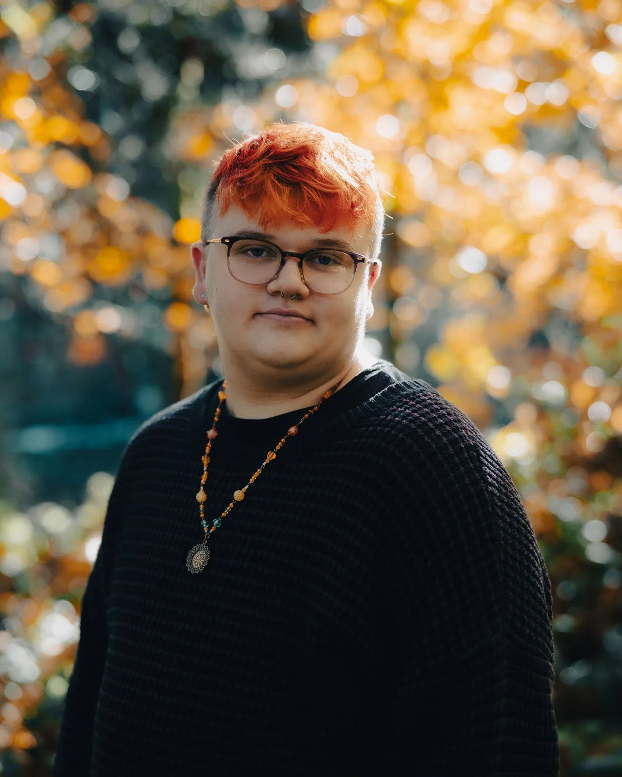 Senior portrait of a boy with orange hair surrounded by fall colors