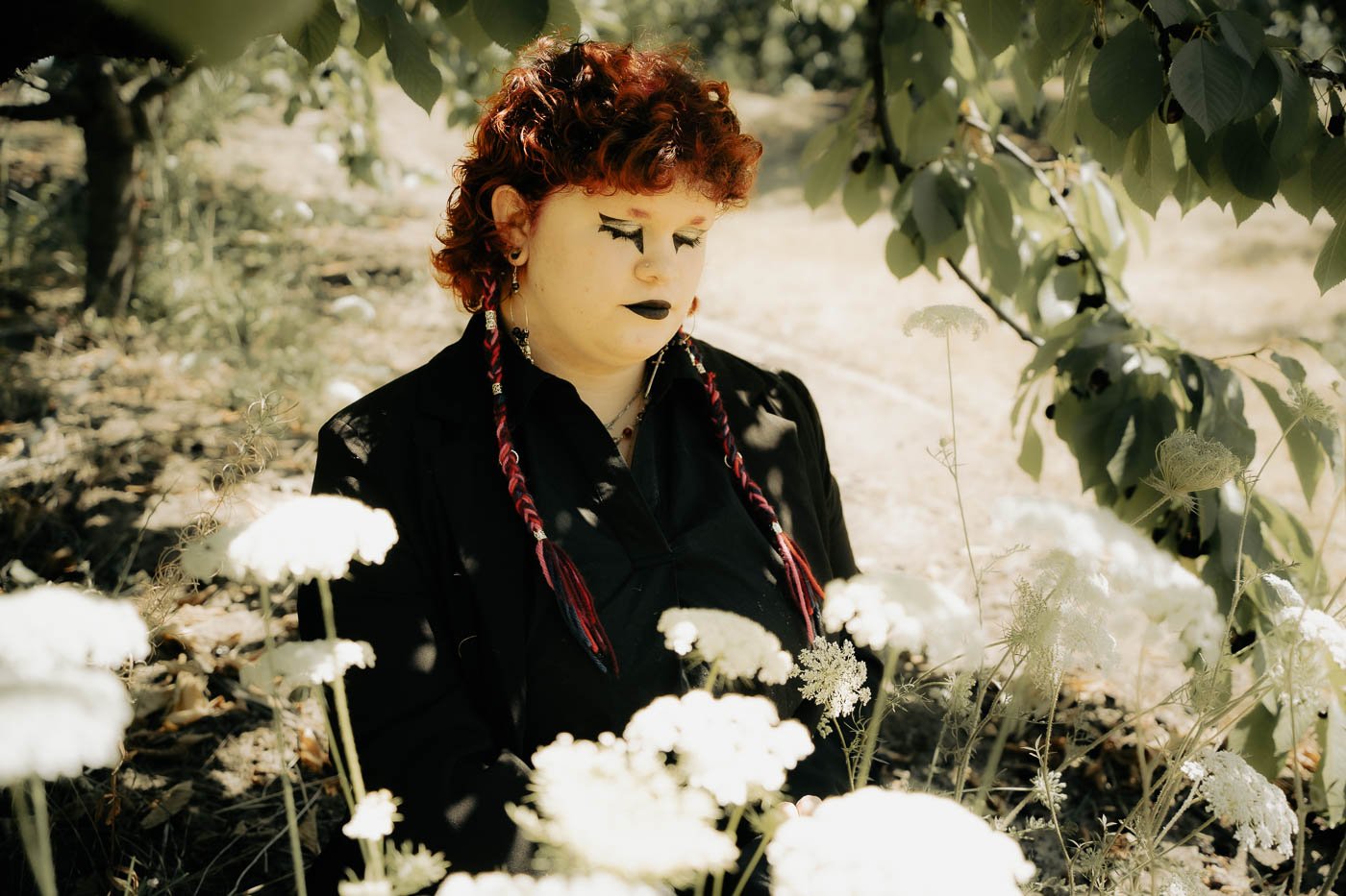 Surrounded by a field of white flowers, a girl sitting under a tree