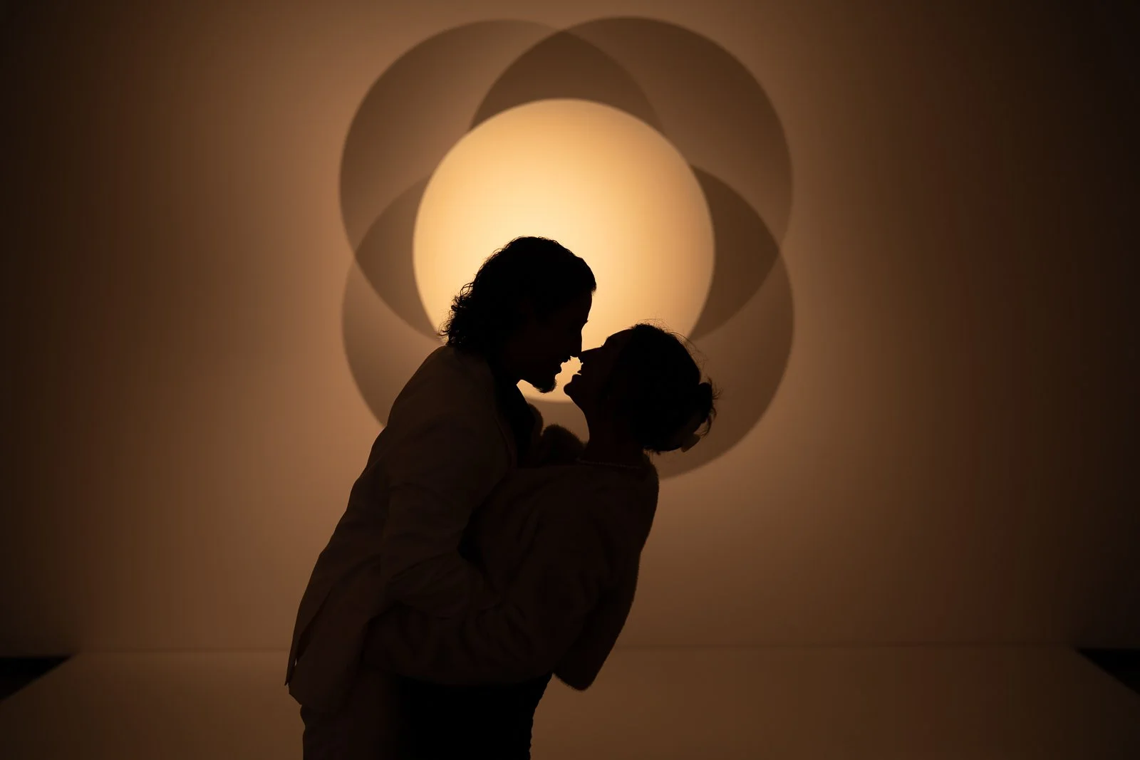 Silhouette of a couple about to kiss in front of a Portland Art Museum exhibit