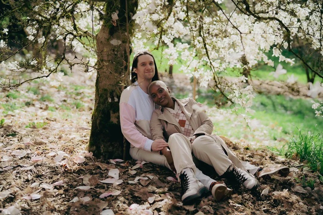 Interracial couple sitting under a flowering magnolia tree