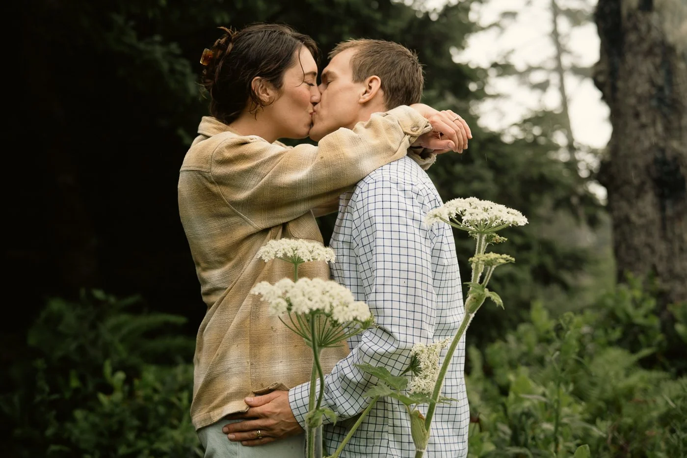 Kissing couple surrounded by forest and flowers at the Oregon Coast