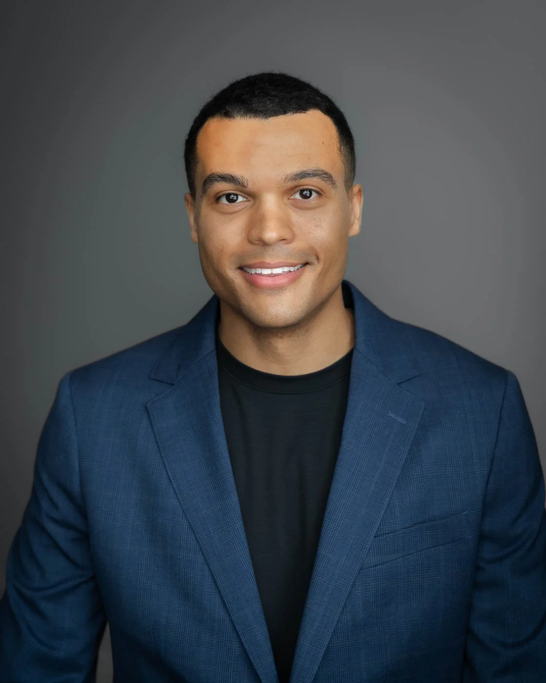 Headshot of man with a friendly smile against a dark grey background