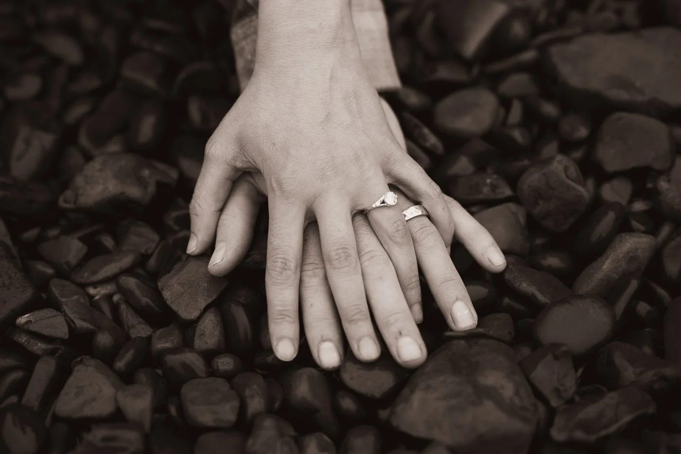 A couple holding hands with their engagement rings at Indian Beach