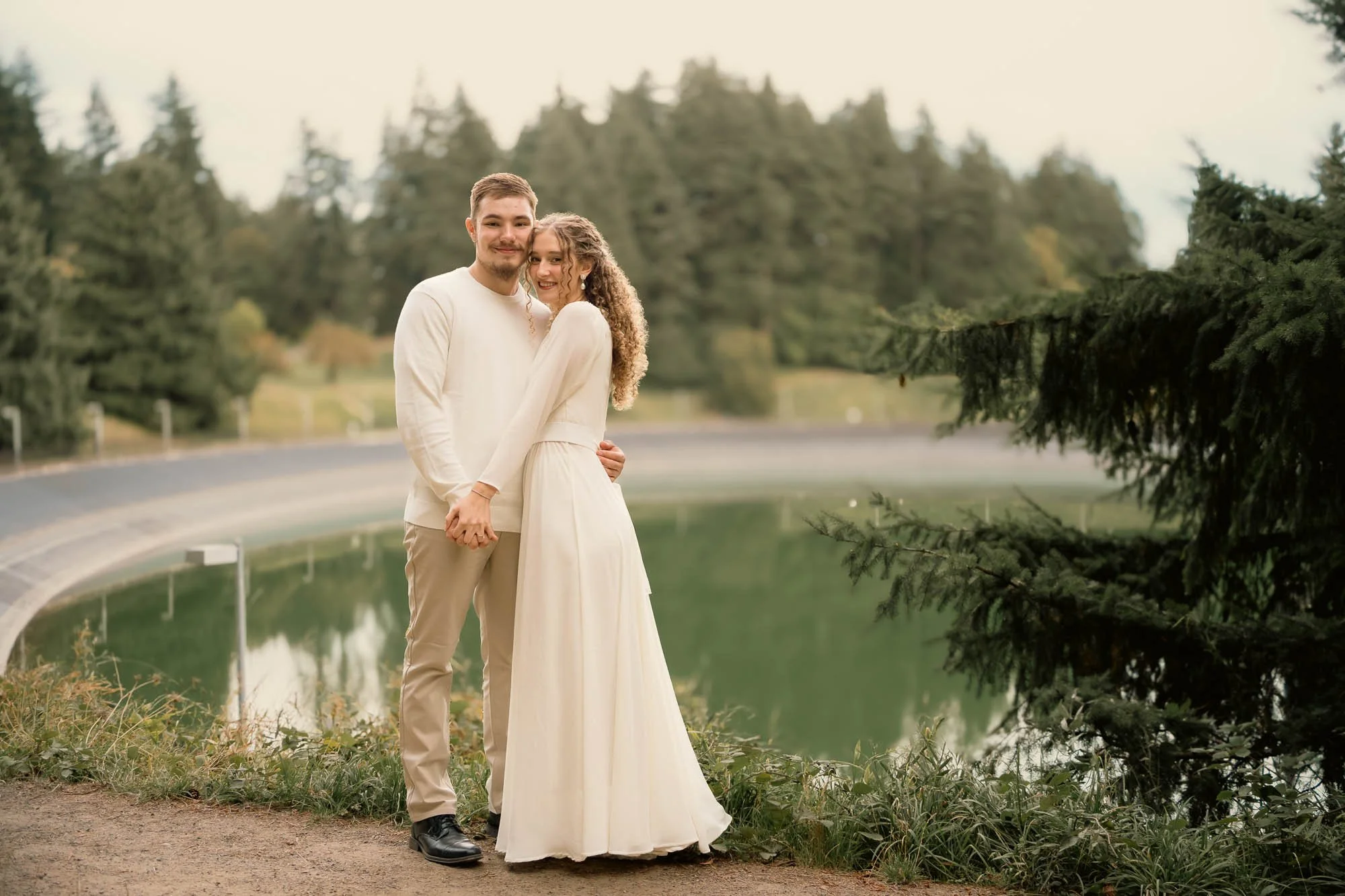 Engaged couple holding hands in matching white outfits