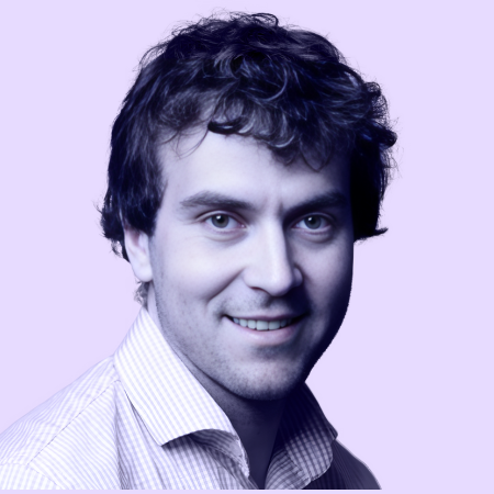 Portret van een jonge man met donker krullend haar, lichte huid en een lichte blauwe en witte gestreepte overhemddoek, lachend en kijkend naar de camera met een paarse achtergrond.