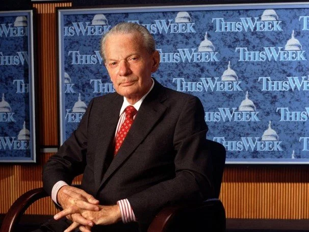 A man in a black suit and red tie sitting in a news studio with 'This Week' logos in the background.
