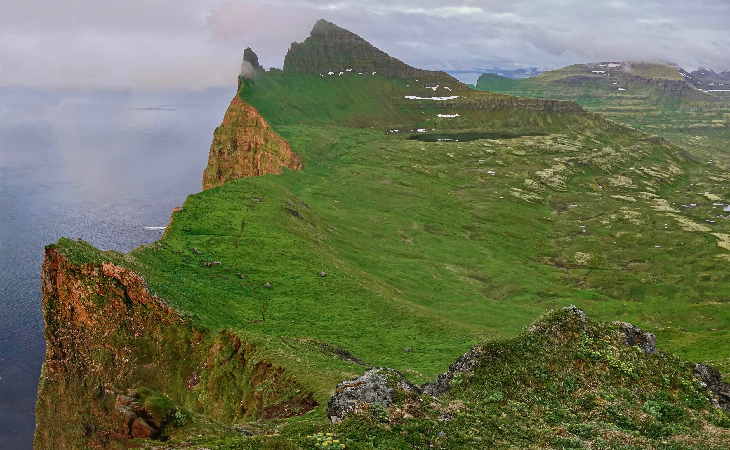 Midnight sun giving an orange glow to the Hornbjarg cliffs of Hornstrandir, Iceland hike