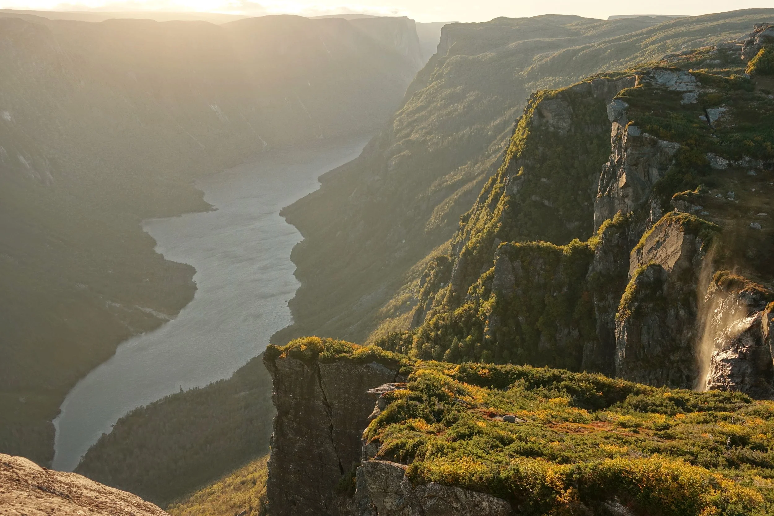 Sunset overlooking Western Brook Pond near a waterfall on the Northern Traverse in Gros Morne National Park hike