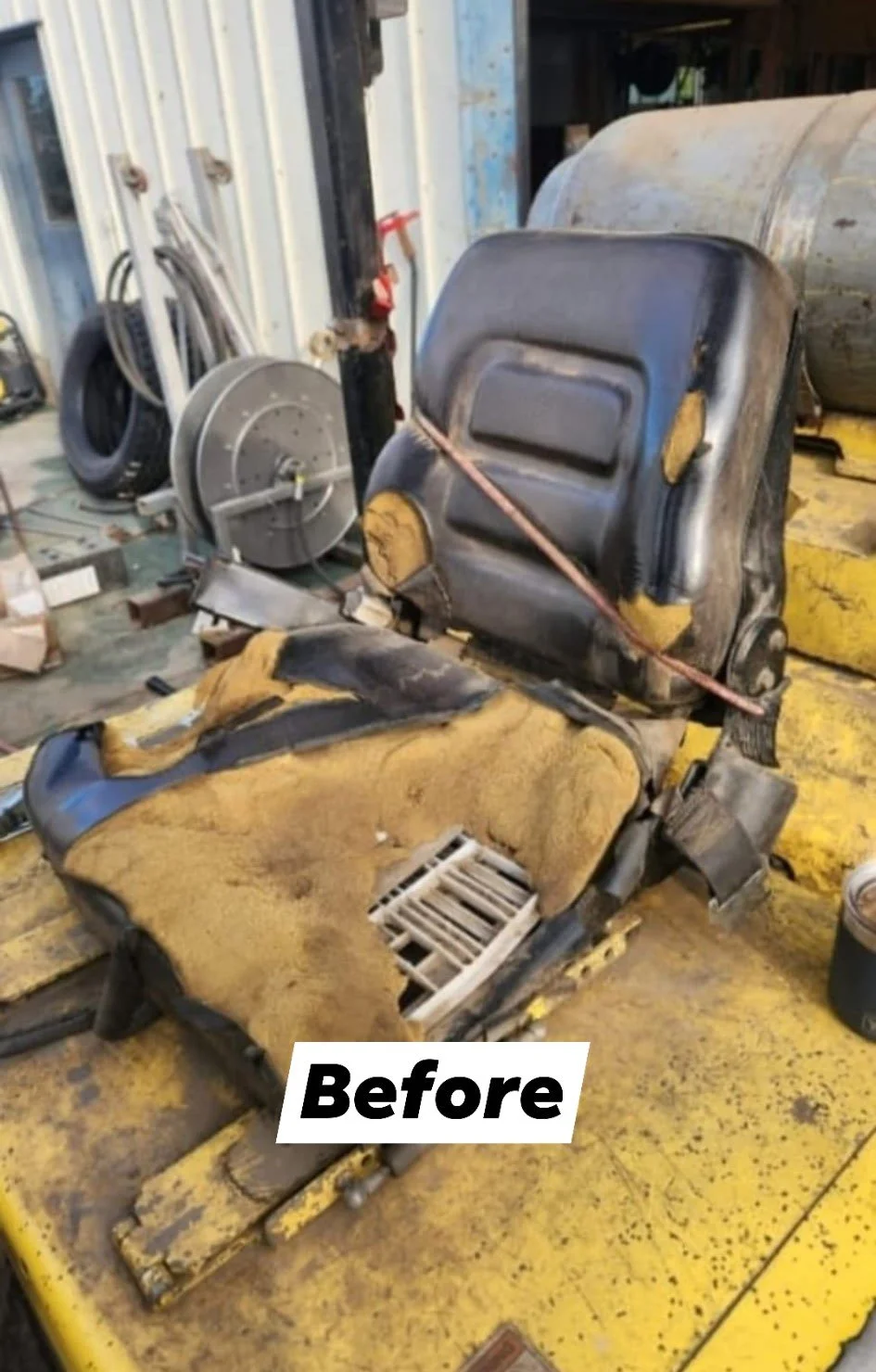 A heavily worn old forklift seat with yellow and black upholstery, showing signs of significant damage and tear, in a workshop setting.