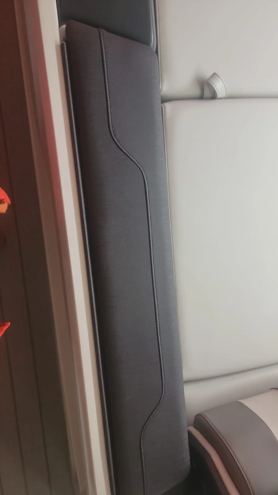 Close-up of folded seats in a vehicle, with dark gray and light gray upholstery and a part of a wooden floor visible.