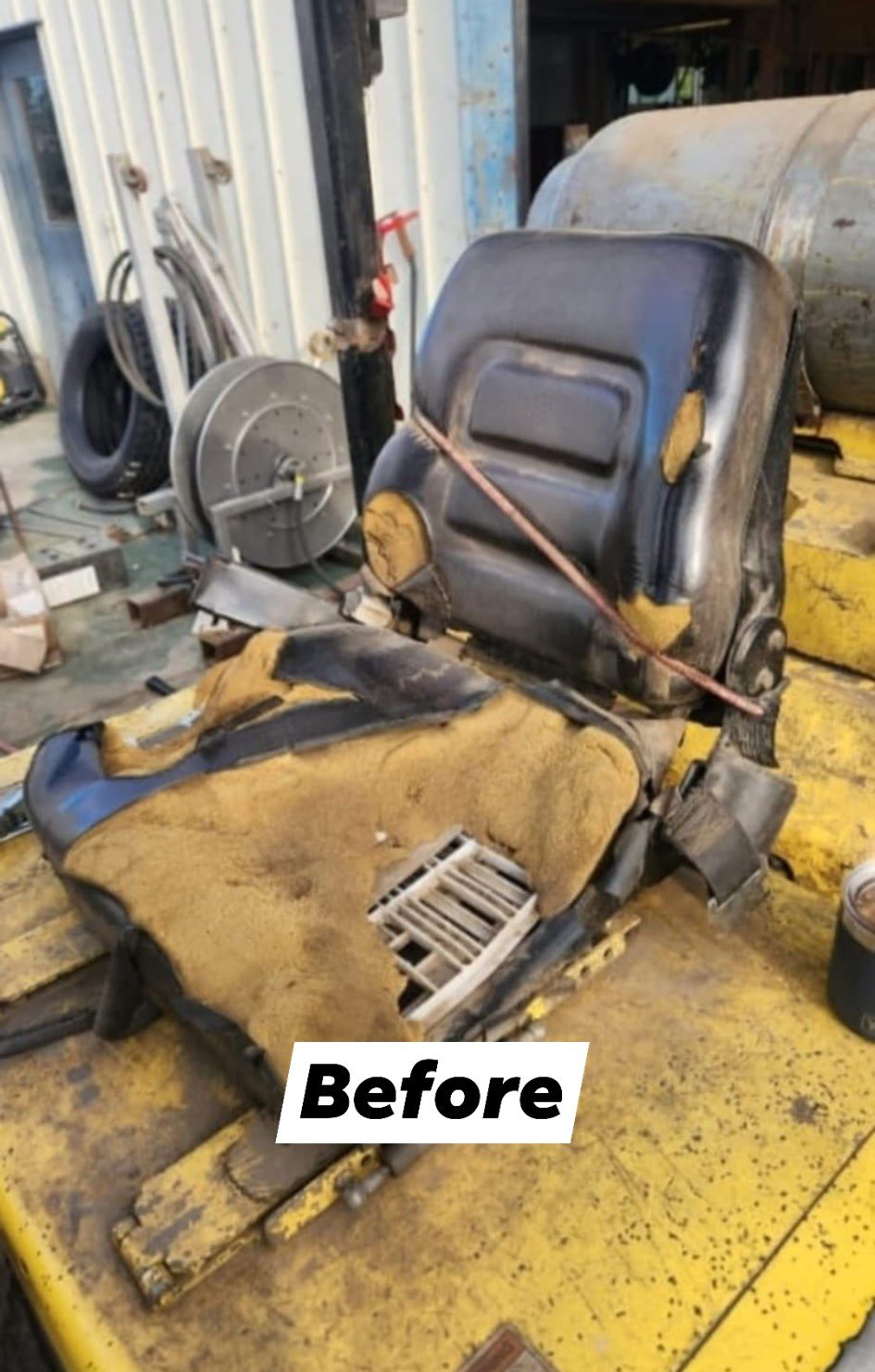 A worn and damaged car seat in a workshop, with a yellow and black color scheme, showing tears, dirt, and interior deterioration.