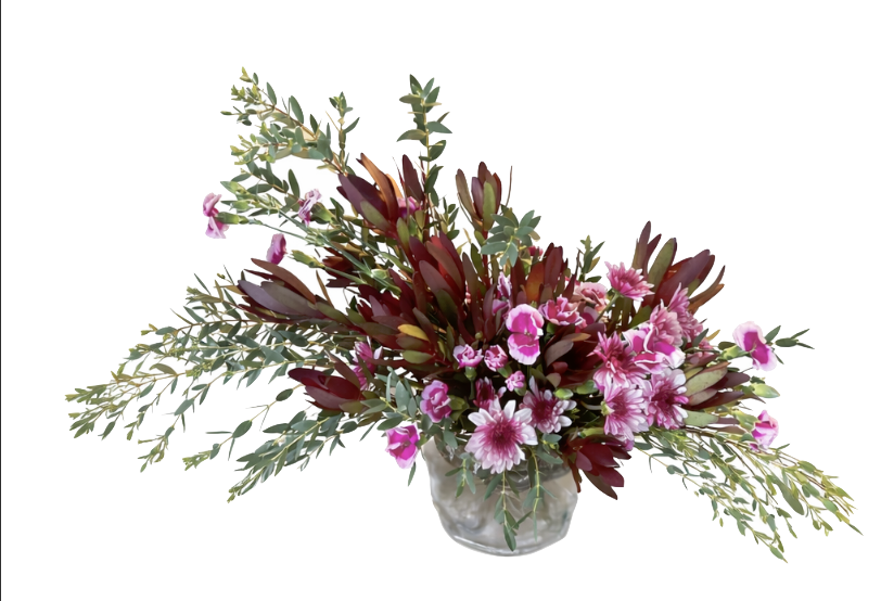 Flower arrangement with pink flowers and green and dark red foliage in a glass vase.