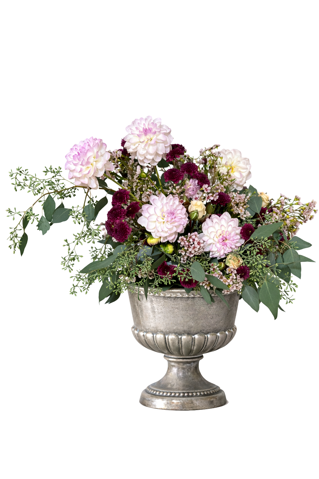 A silver urn filled with a bouquet of pink and white dahlias, dark purple carnations, small pink flowers, and green foliage.