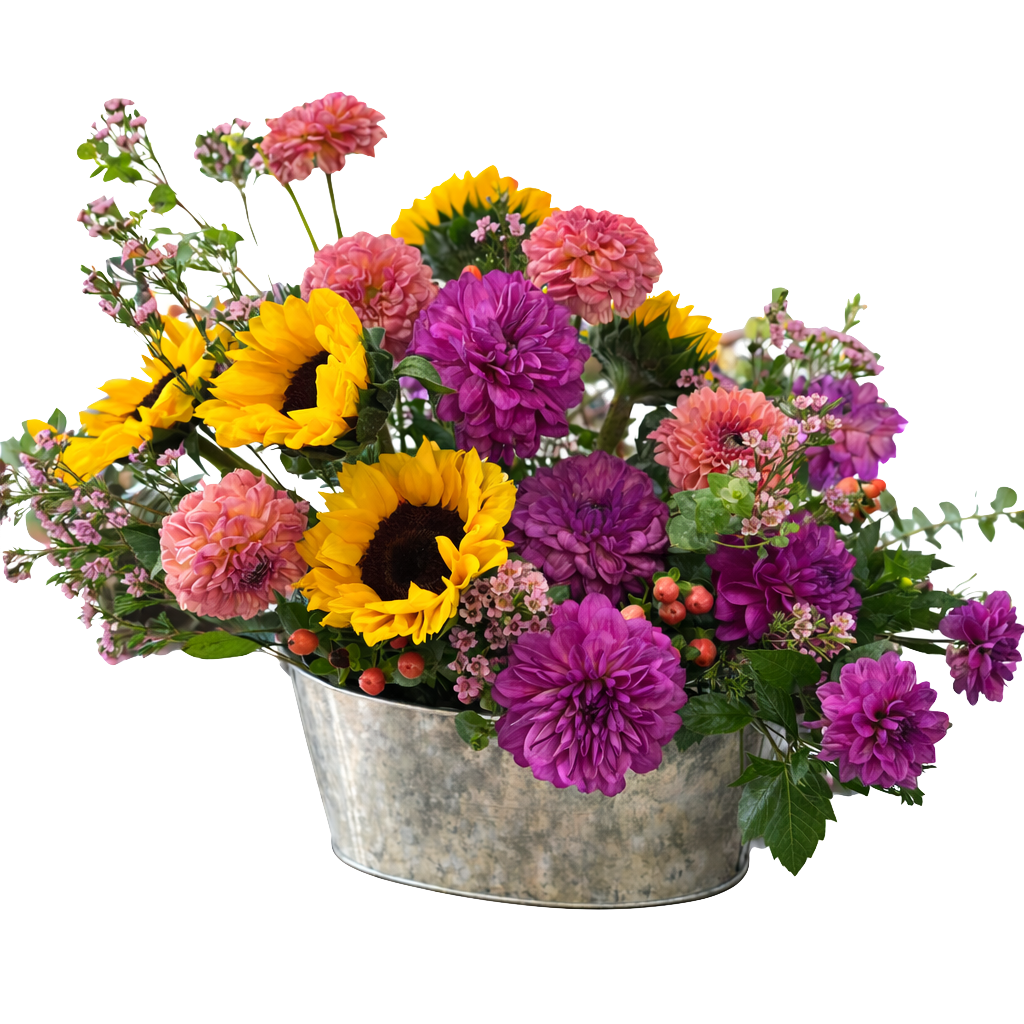 A metal bucket filled with a colorful mixture of pink, purple, and yellow flowers, including sunflowers, dahlias, and other small blossoms.