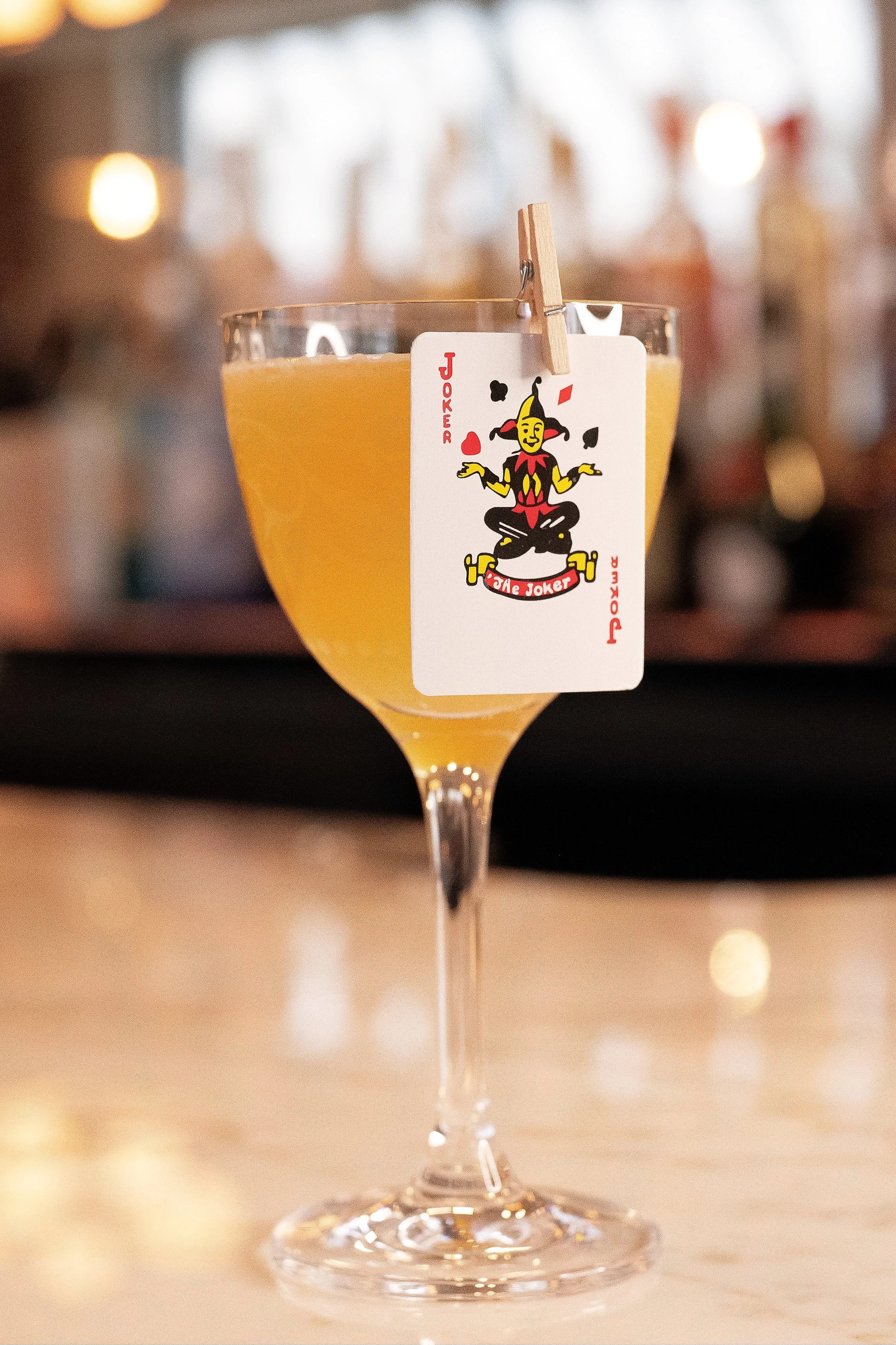 Unique 'Joker' craft cocktail served with a playing card garnish at the bar of Viv & Jules Hoboken.