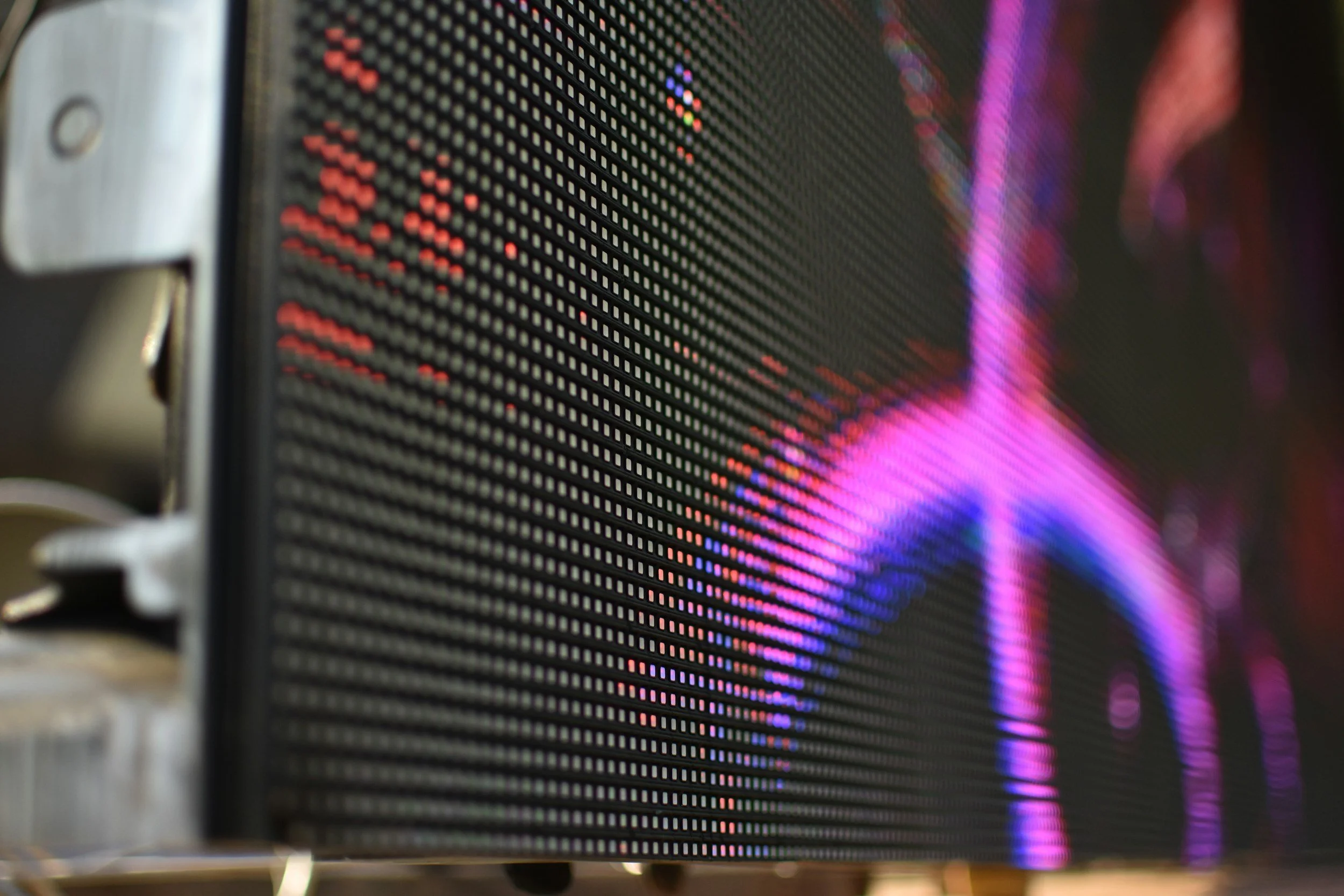 Close-up of a digital LED display screen showing colorful, abstract graphics in pink, purple, and blue hues.