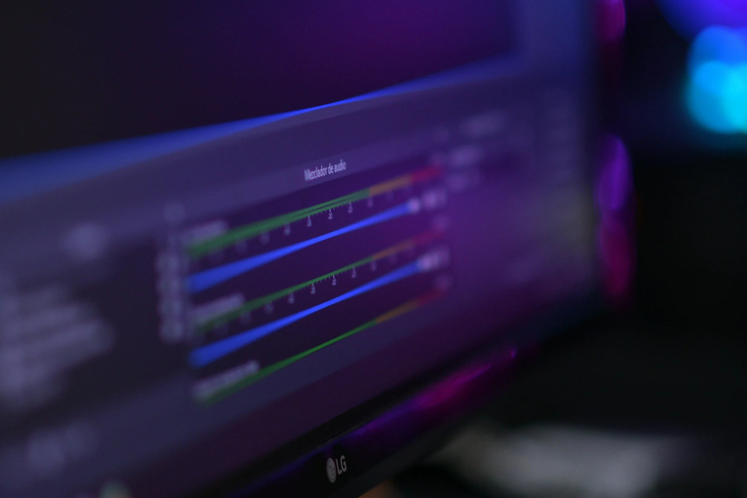 Close-up photo of an audio mixer screen displaying multiple colorful sliders and levels, with the brand LG visible at the bottom of the monitor.