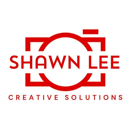 A logo with a stylized red camera outline, featuring the text 'SHAWN LEE' in bold red letters across the center and 'CREATIVE SOLUTIONS' in smaller red letters below.