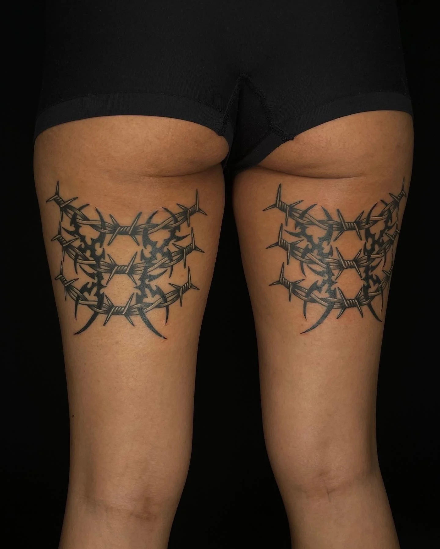 matching tribal and barbed wire thigh tattoos